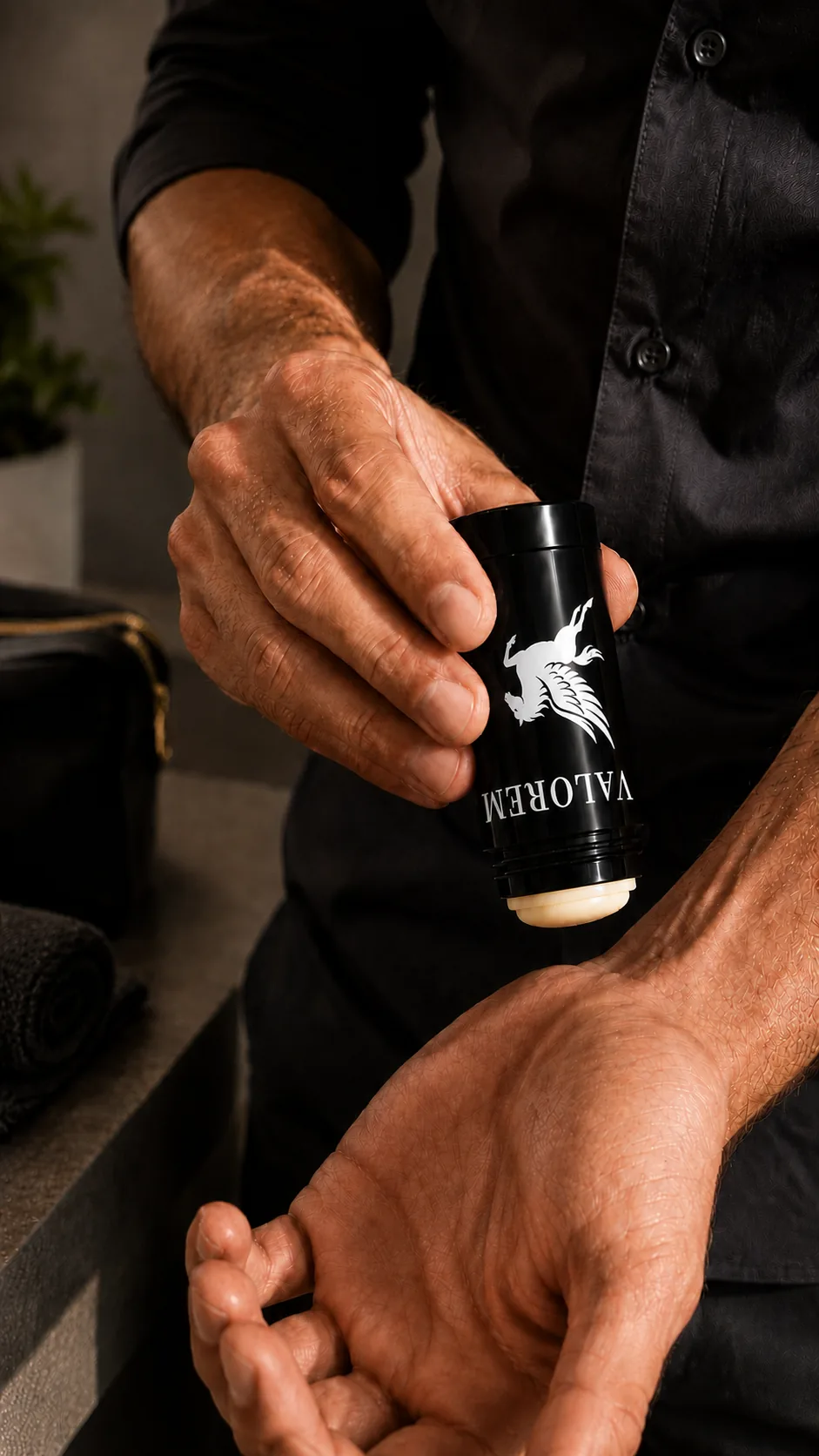 A hand twisting up a Valorem solid fragrance stick over an open palm